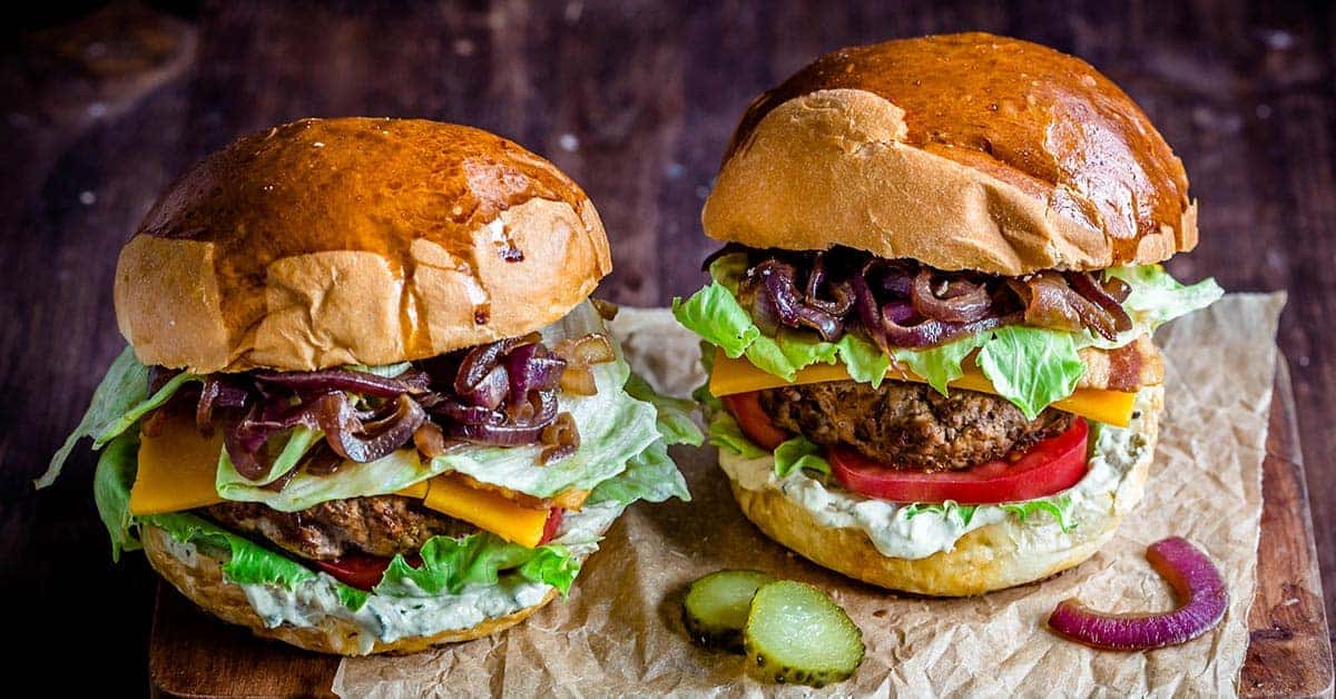 two loaded burgers up close with pickles