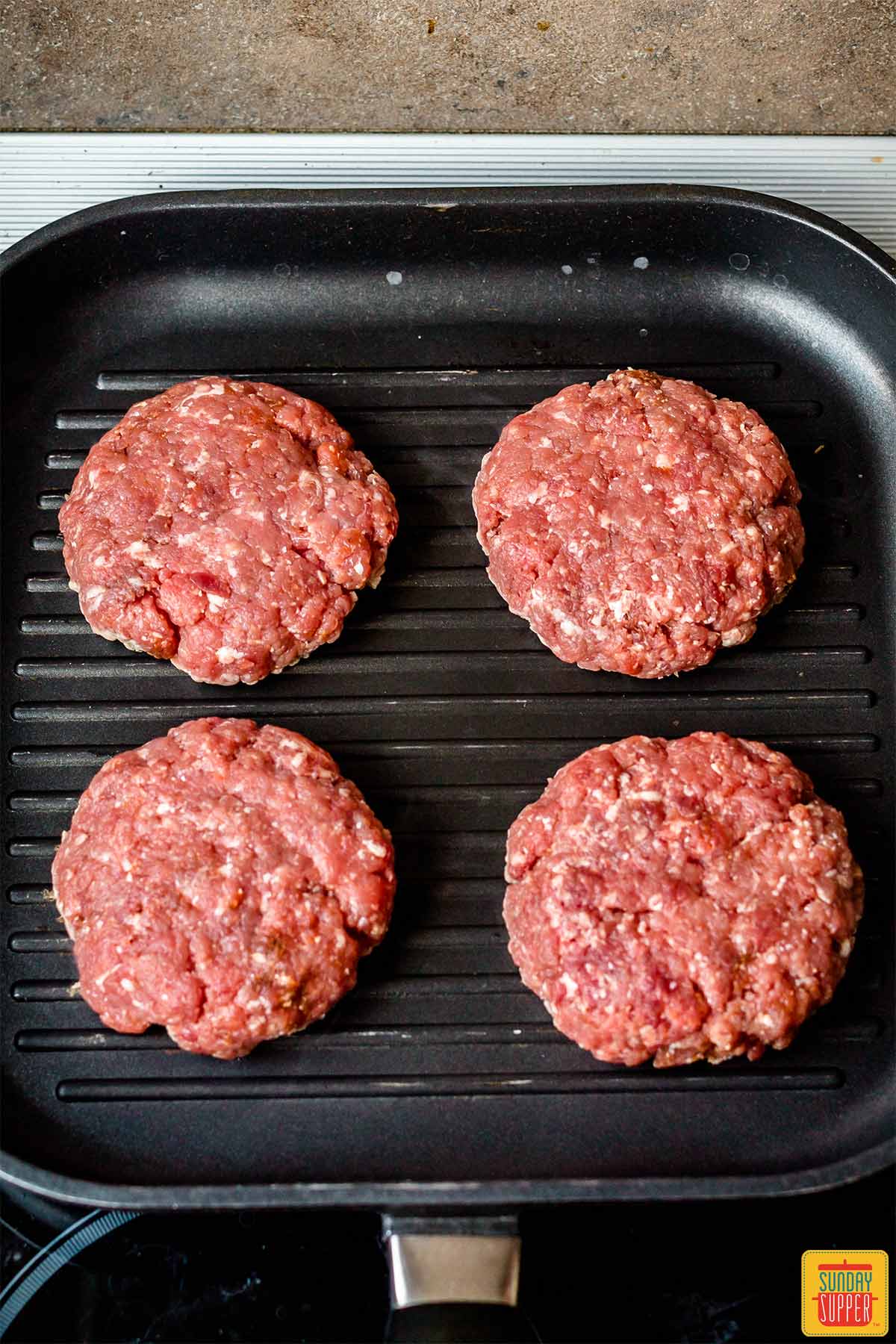 Uncooked burger patties on the grill