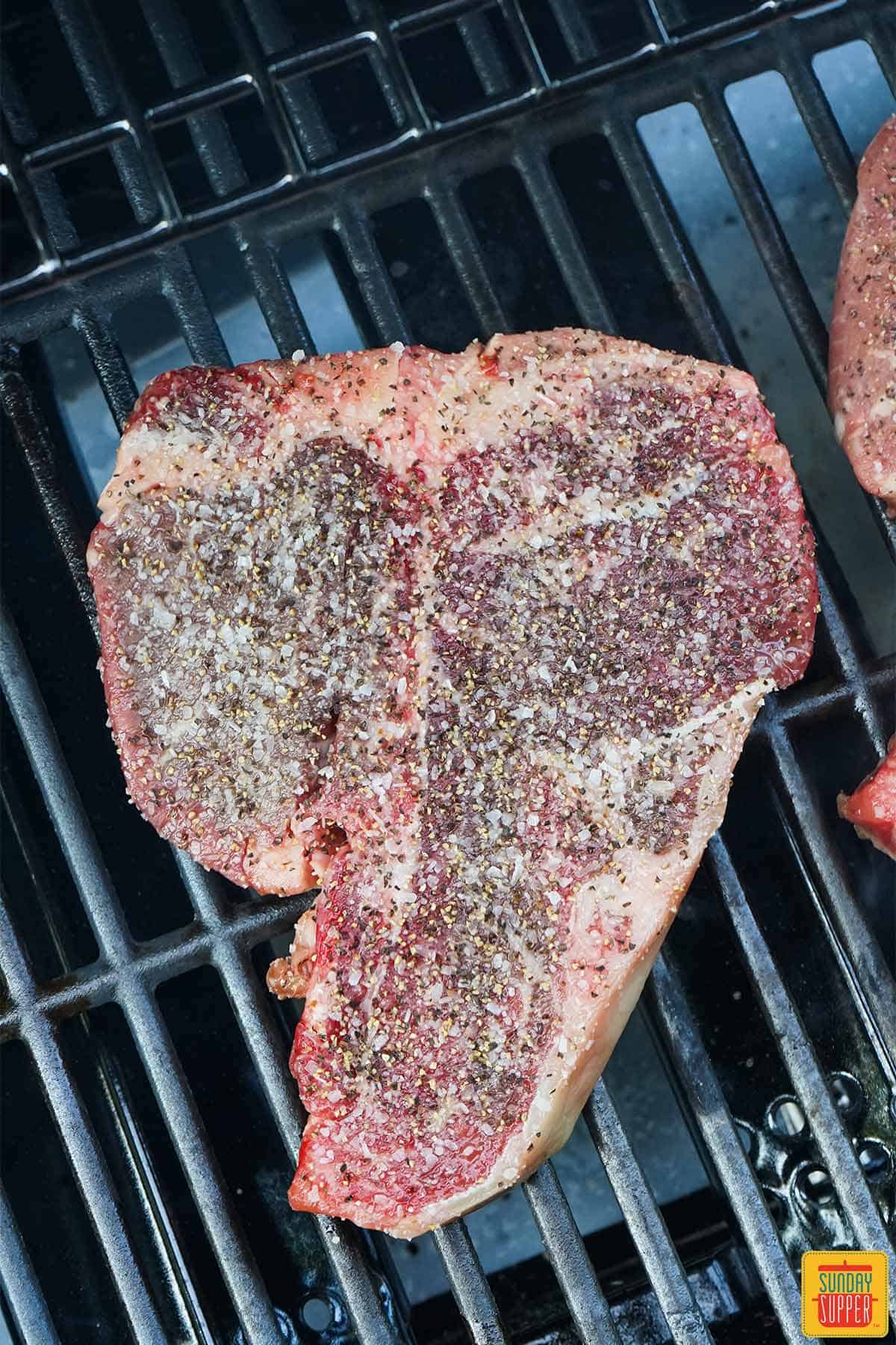 Seasoned steak searing on a grill
