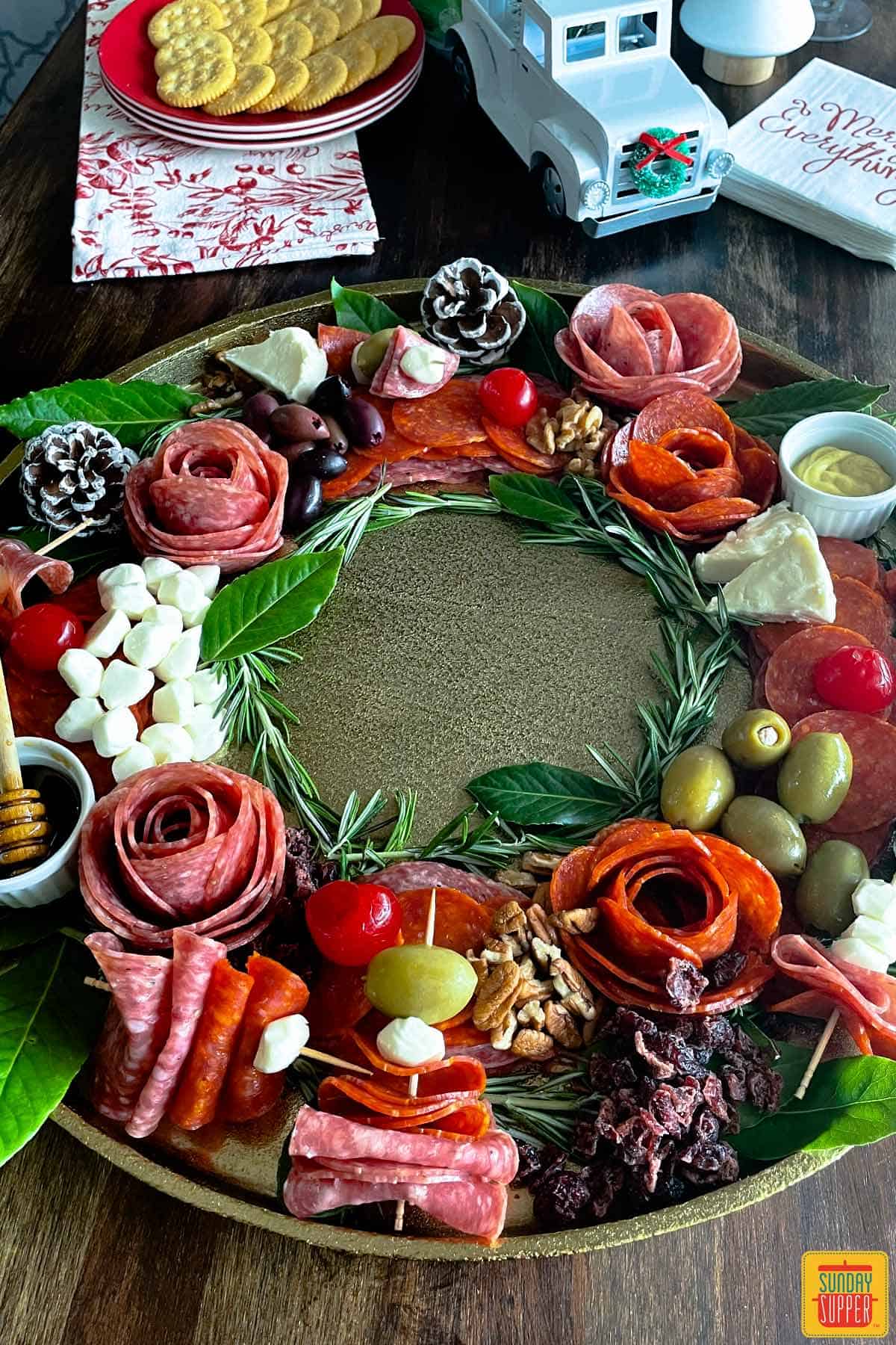 round charcuterie tray with holiday charcuterie offerings next to holiday decorations