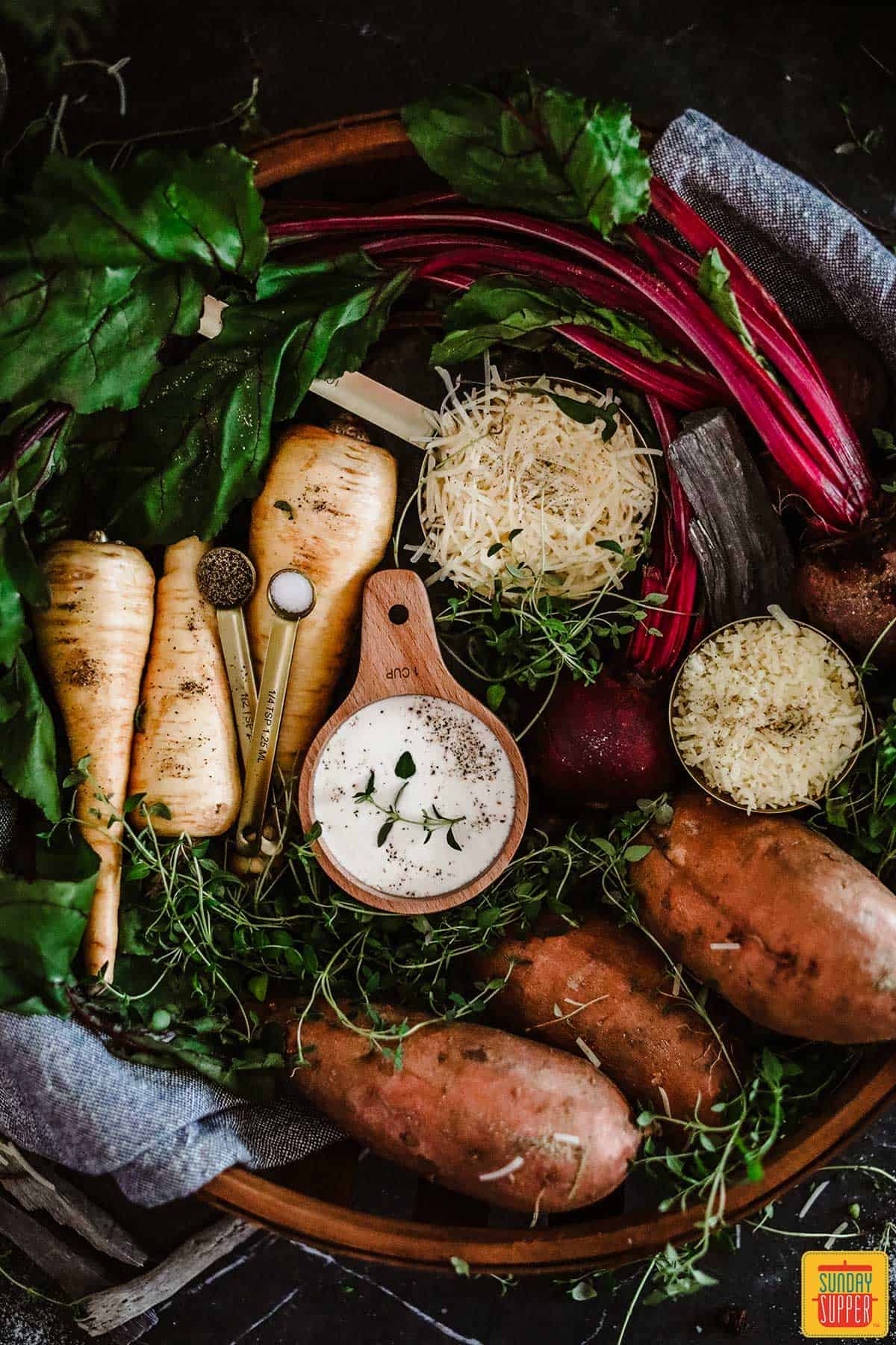 Ingredients to make vegetable au gratin in a large round basket