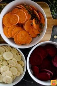thinly sliced parsnips, beets, and sweet potatoes in individual bowls