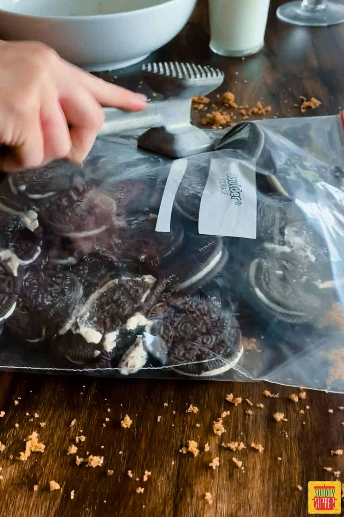 Pounding oreo cookies into small pieces in a bag