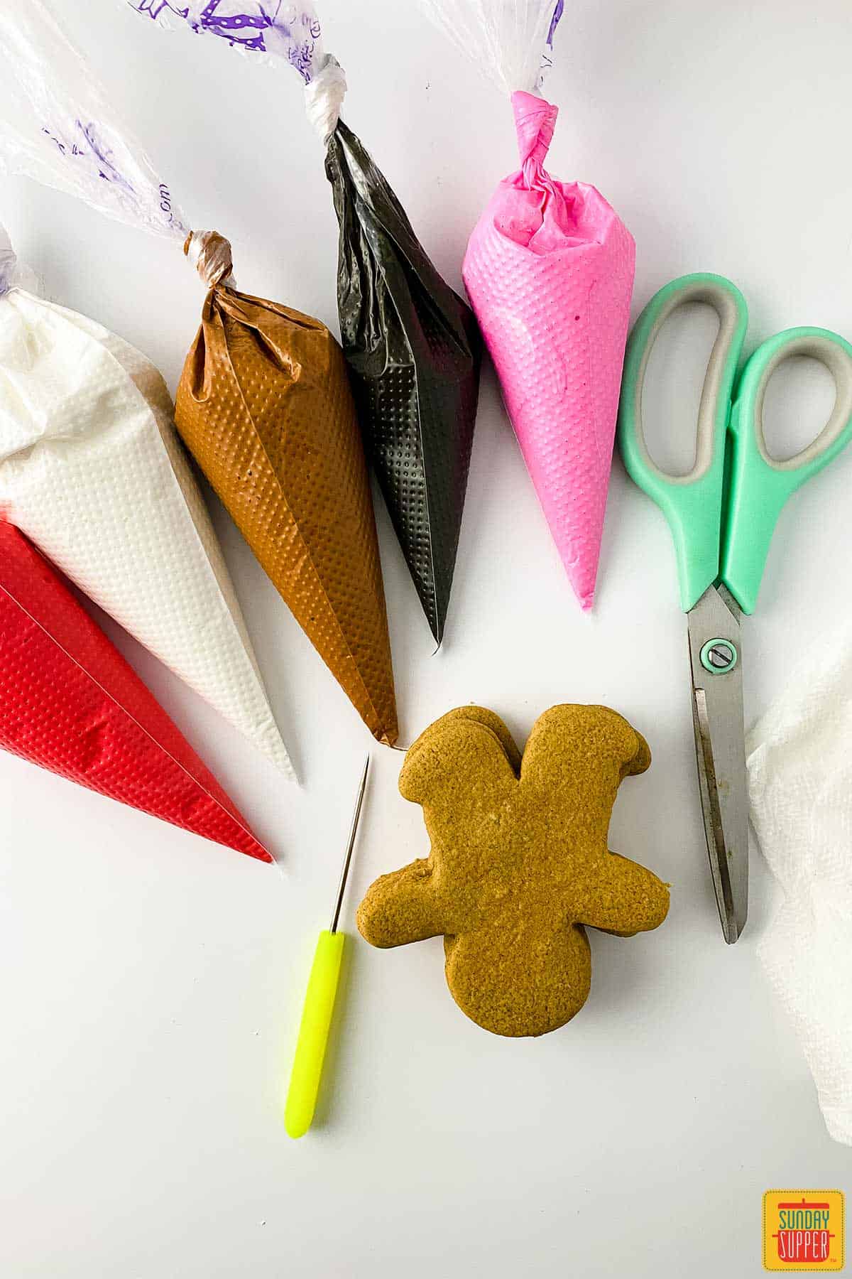 five royal icing bags, scissors, and gingerbread cookies