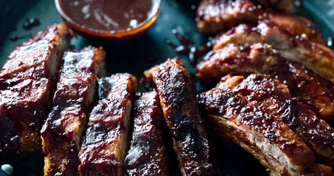Air fryer pork ribs on a black plate with bbq dipping sauce