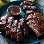 Air fryer pork ribs on a black plate with bbq dipping sauce