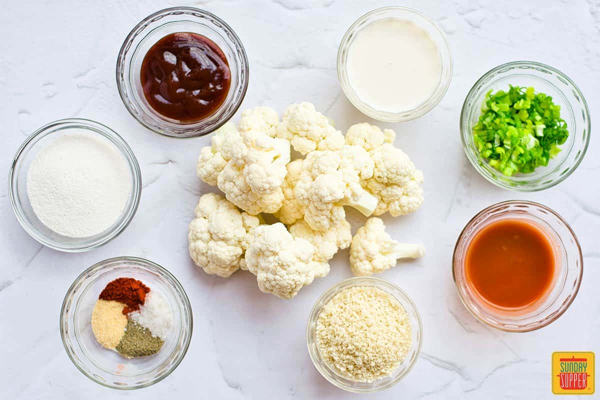 Cauliflower wings ingredients on a white surface in bowls