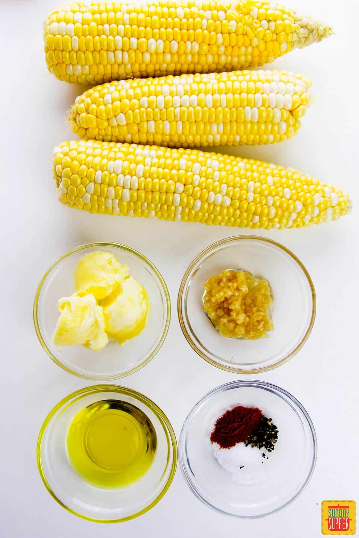 corn ribs ingredients in bowls on a white surface next to corn