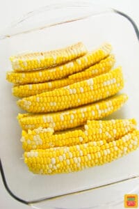 Corn cobs cut into fourths in a glass baking dish