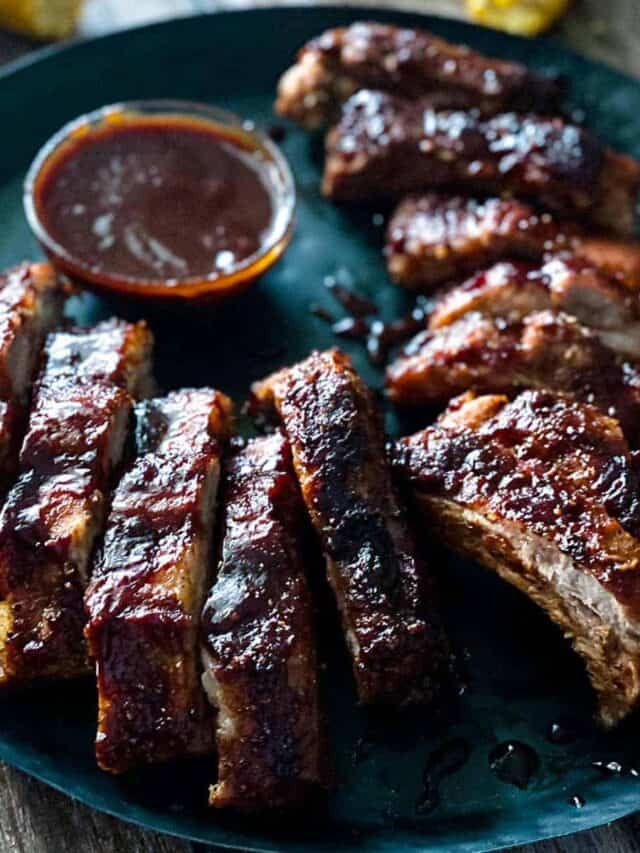 Air fryer pork ribs on a black plate with bbq dipping sauce