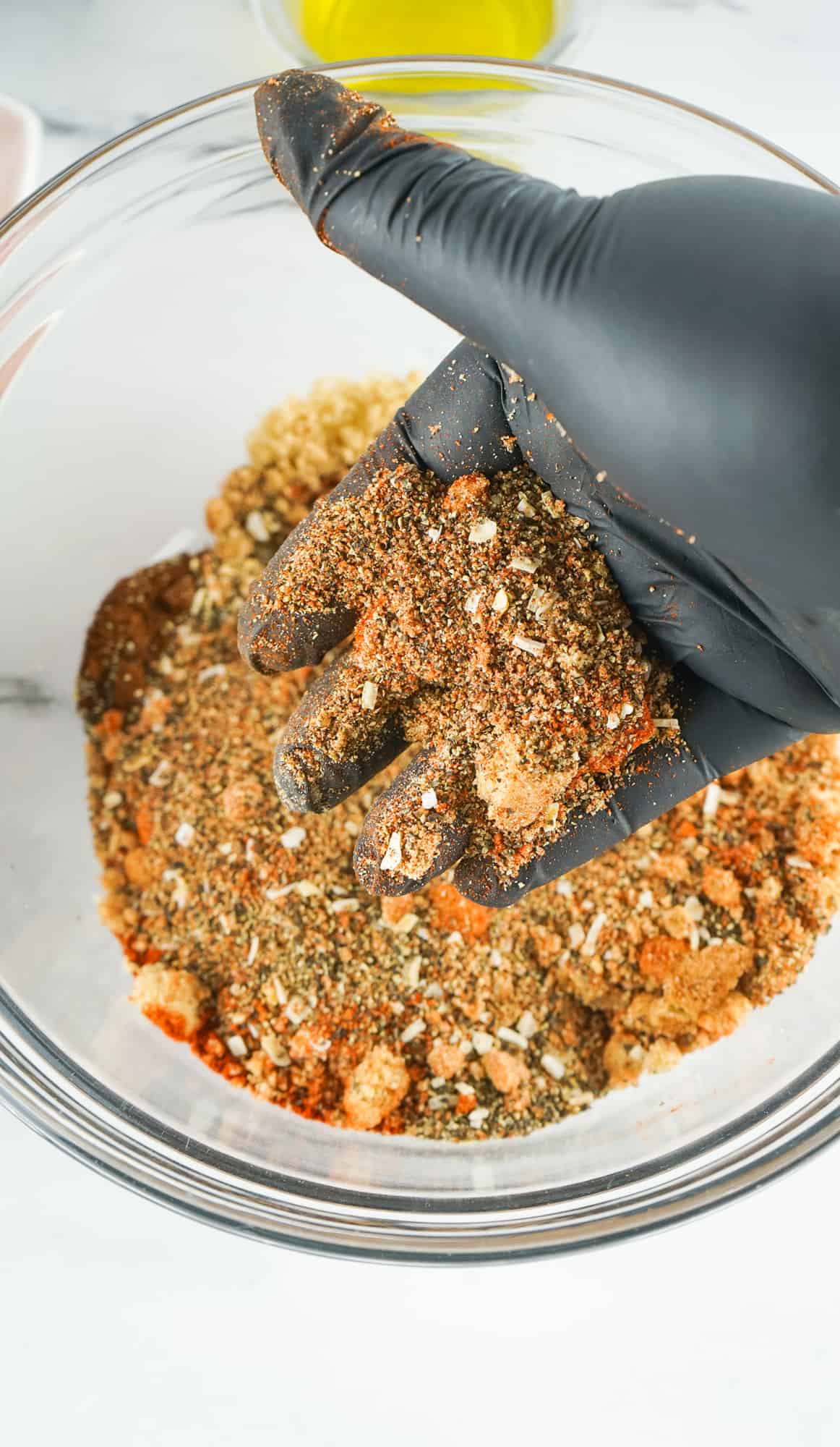 Pork butt seasoning mixture mixed with gloved hand in a bowl