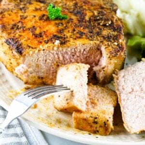 Grilled pork chop sliced on a plate with a fork