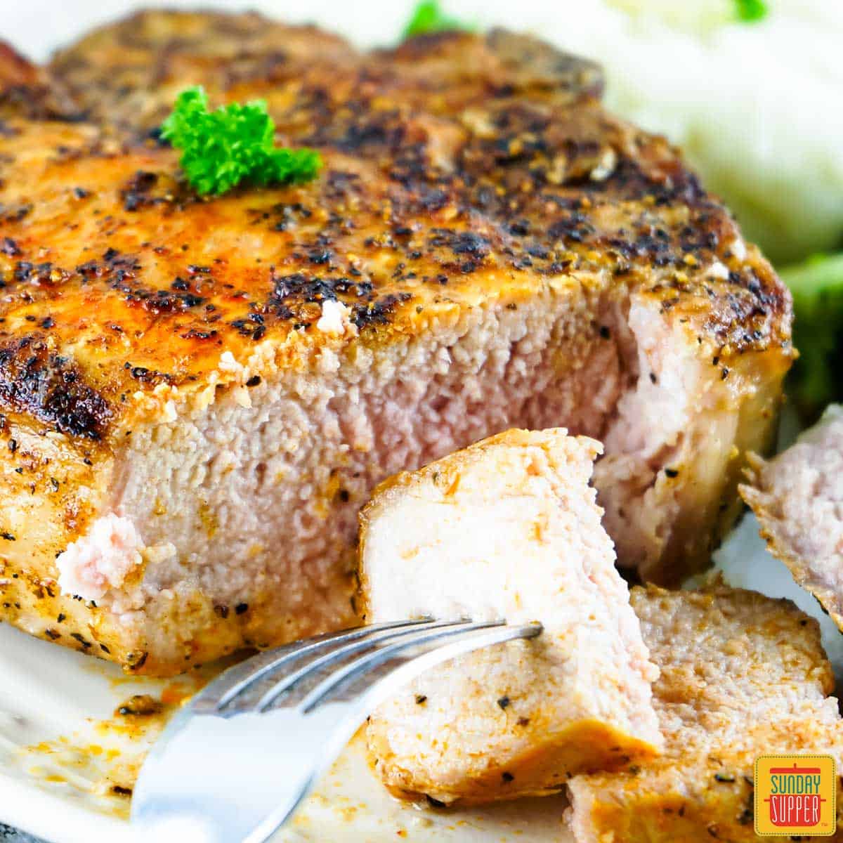 Grilled pork chop sliced on a plate with a fork