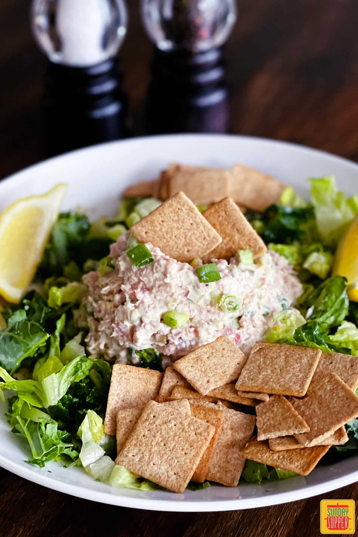 Homemade ham salad recipe served on a plate with crackers and lemon wedges