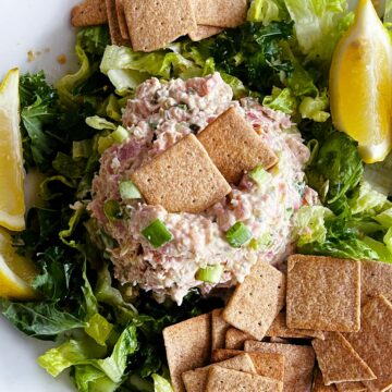 Close up of ham salad on a plate with lemon wedges and crackers