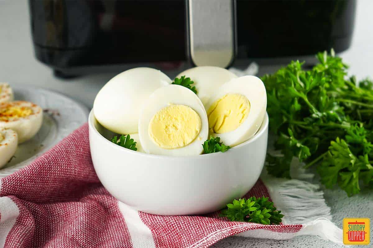 air fryer boiled eggs in a bowl next to air fryer