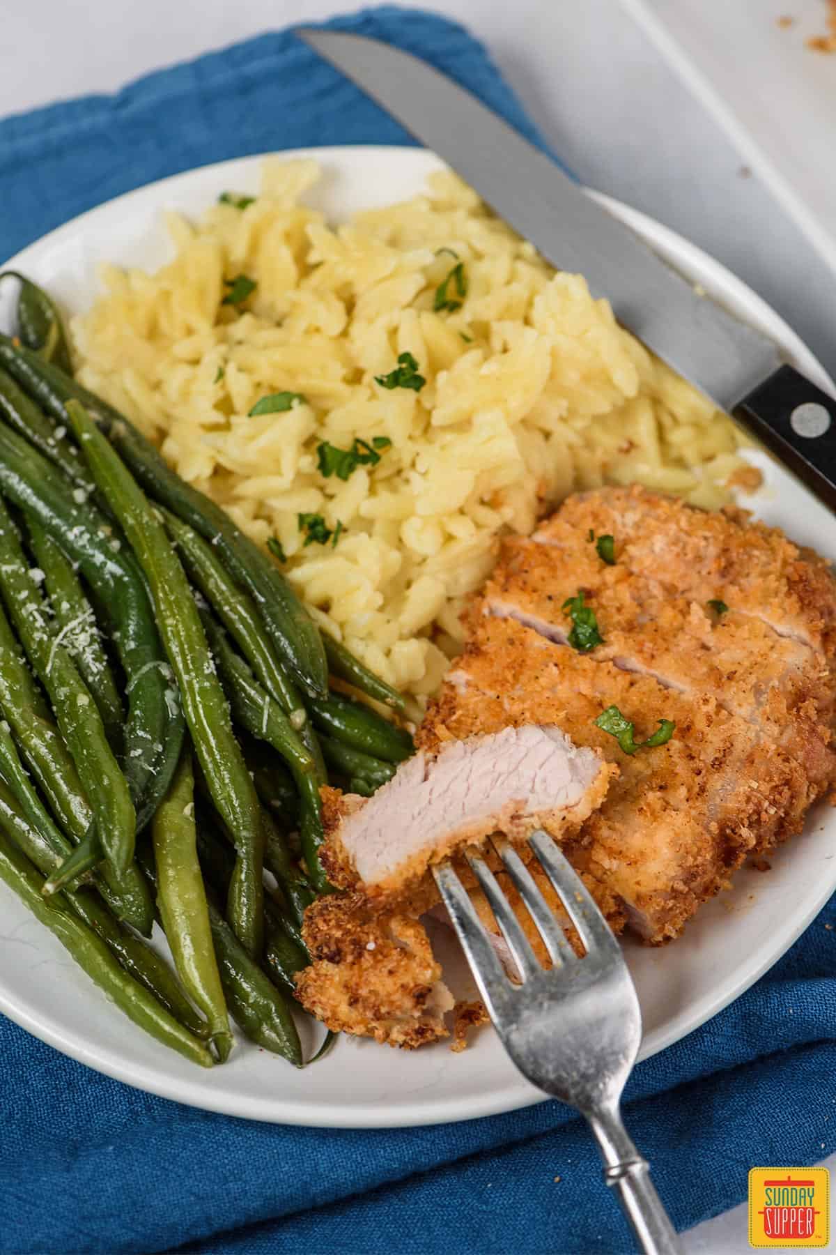 A plate of air fryer pork chops with a forkful of pork chop