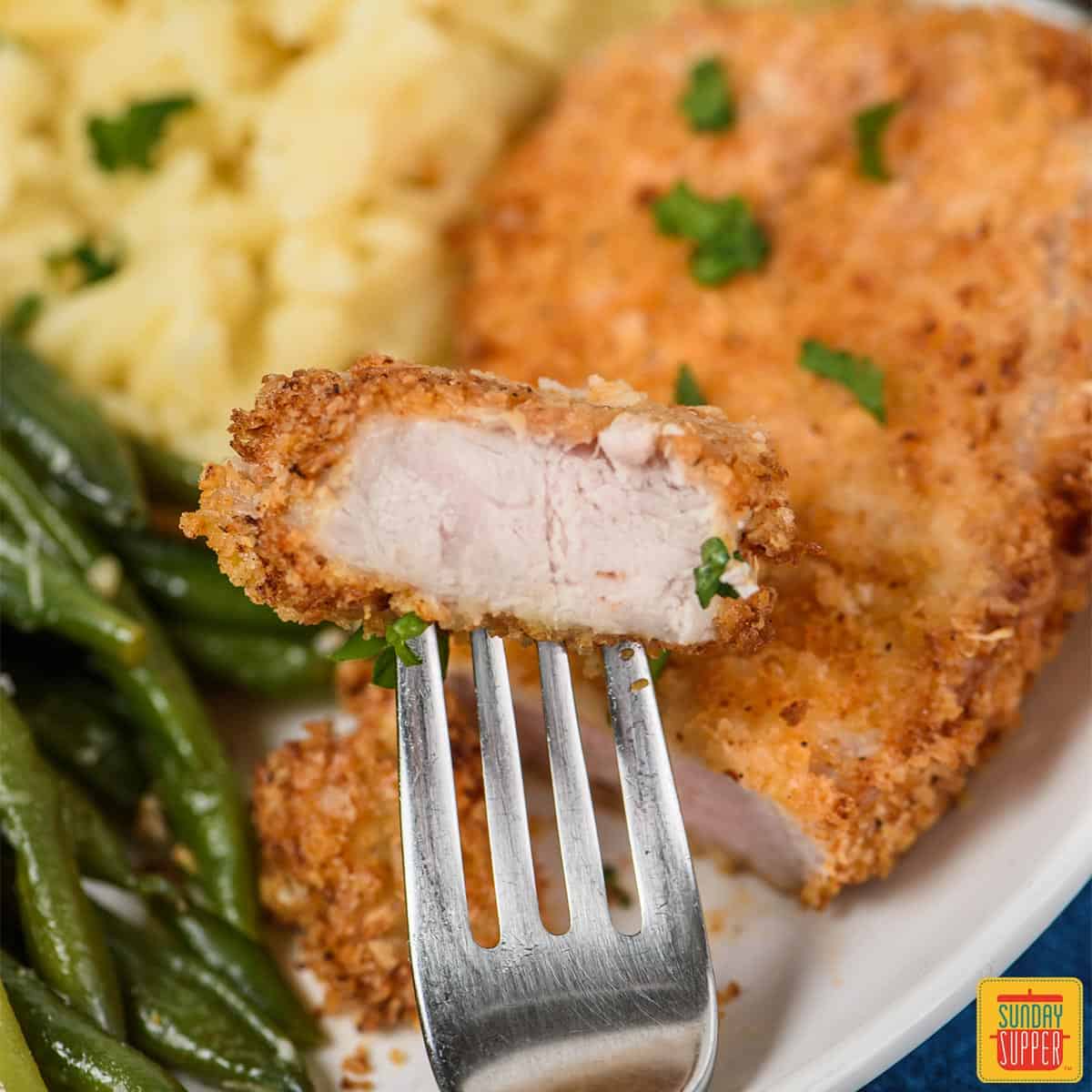 A fork with a bite of air fryer pork chops