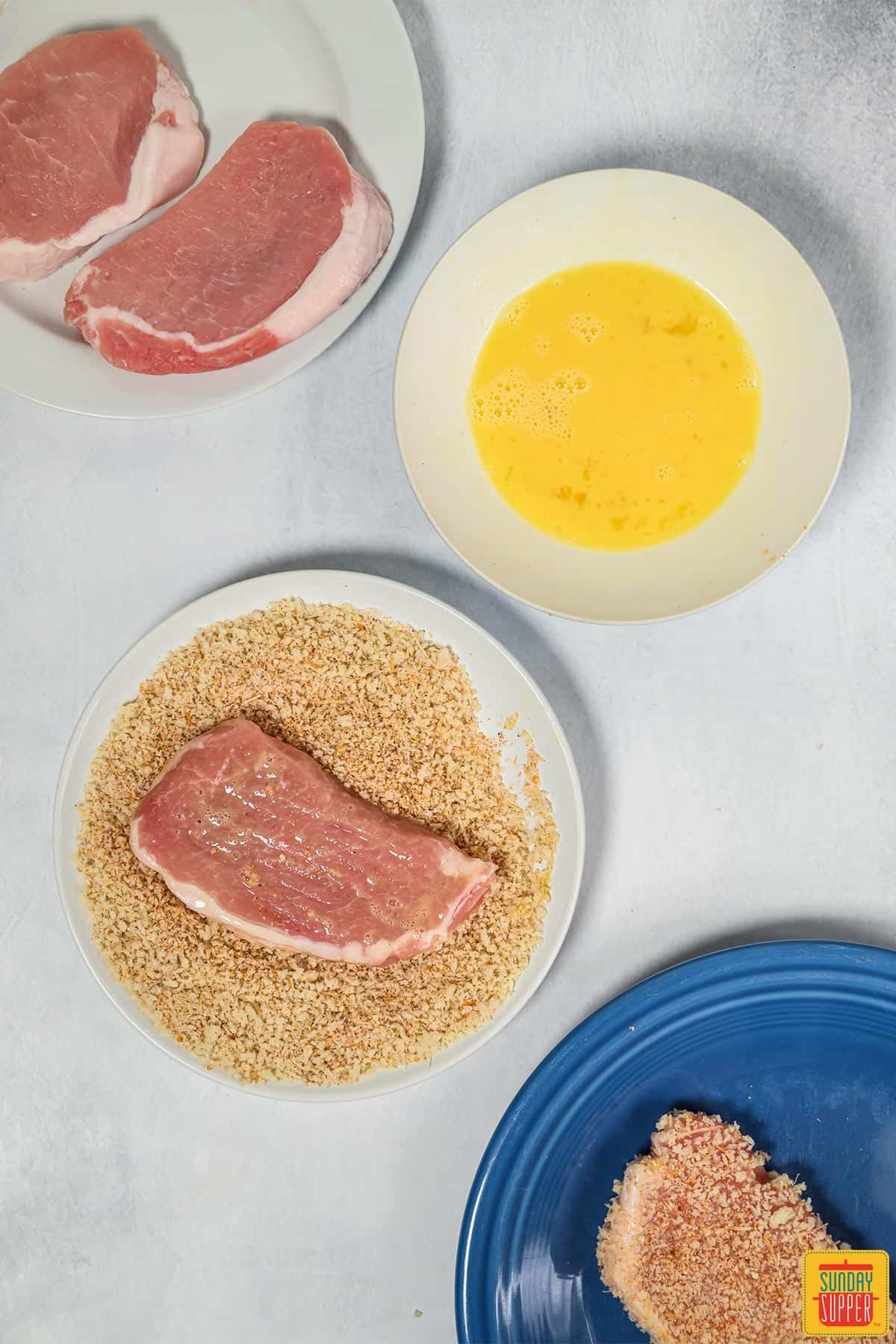 Dredging pork chop in breadcrumbs and egg