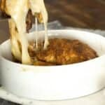 pulling baked brie out of ramekin with gooey cheese