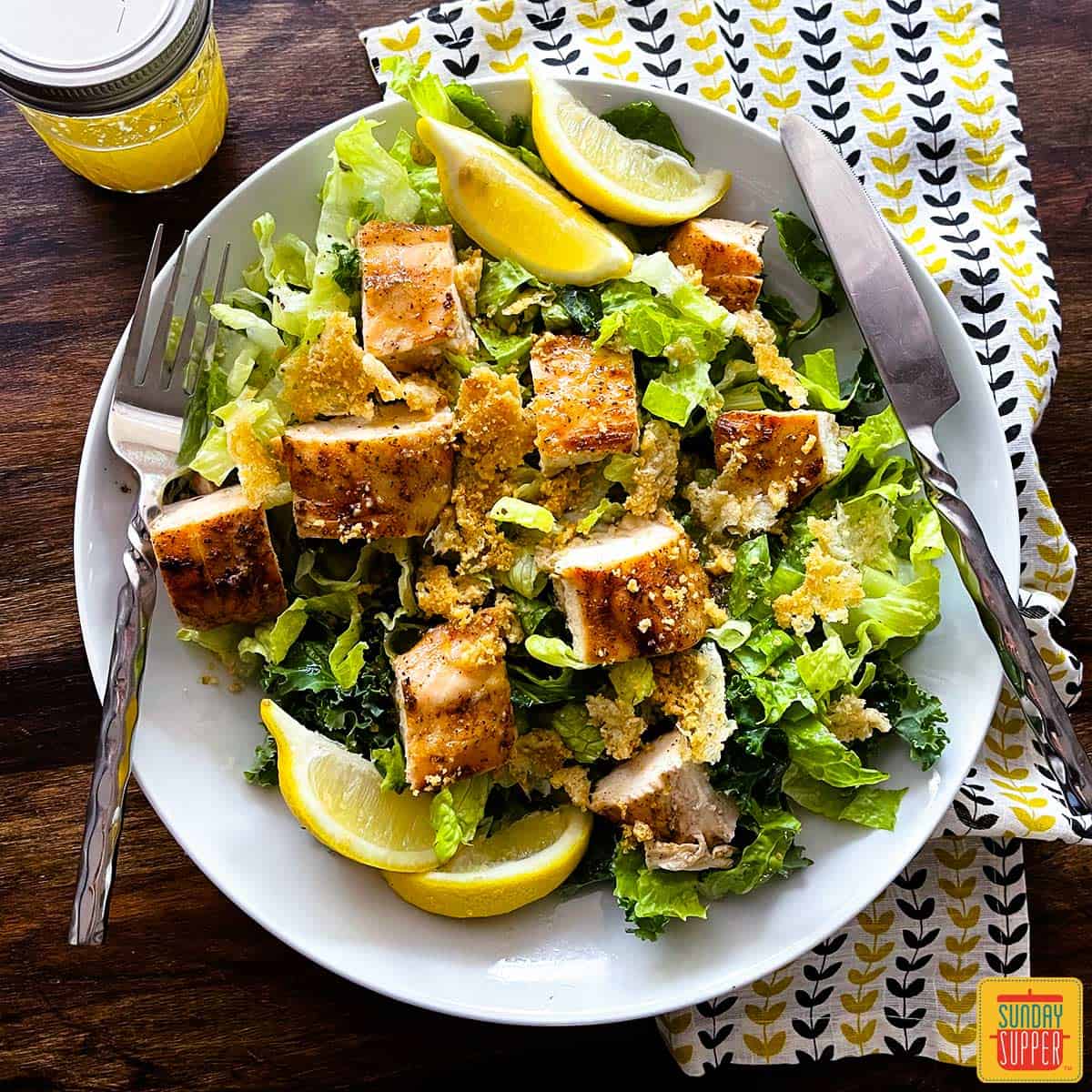 Chick-fil-A kale caesar salad on a plate with lemon wedges and grilled chicken