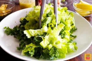 Mixing lettuce on a plate with tongs