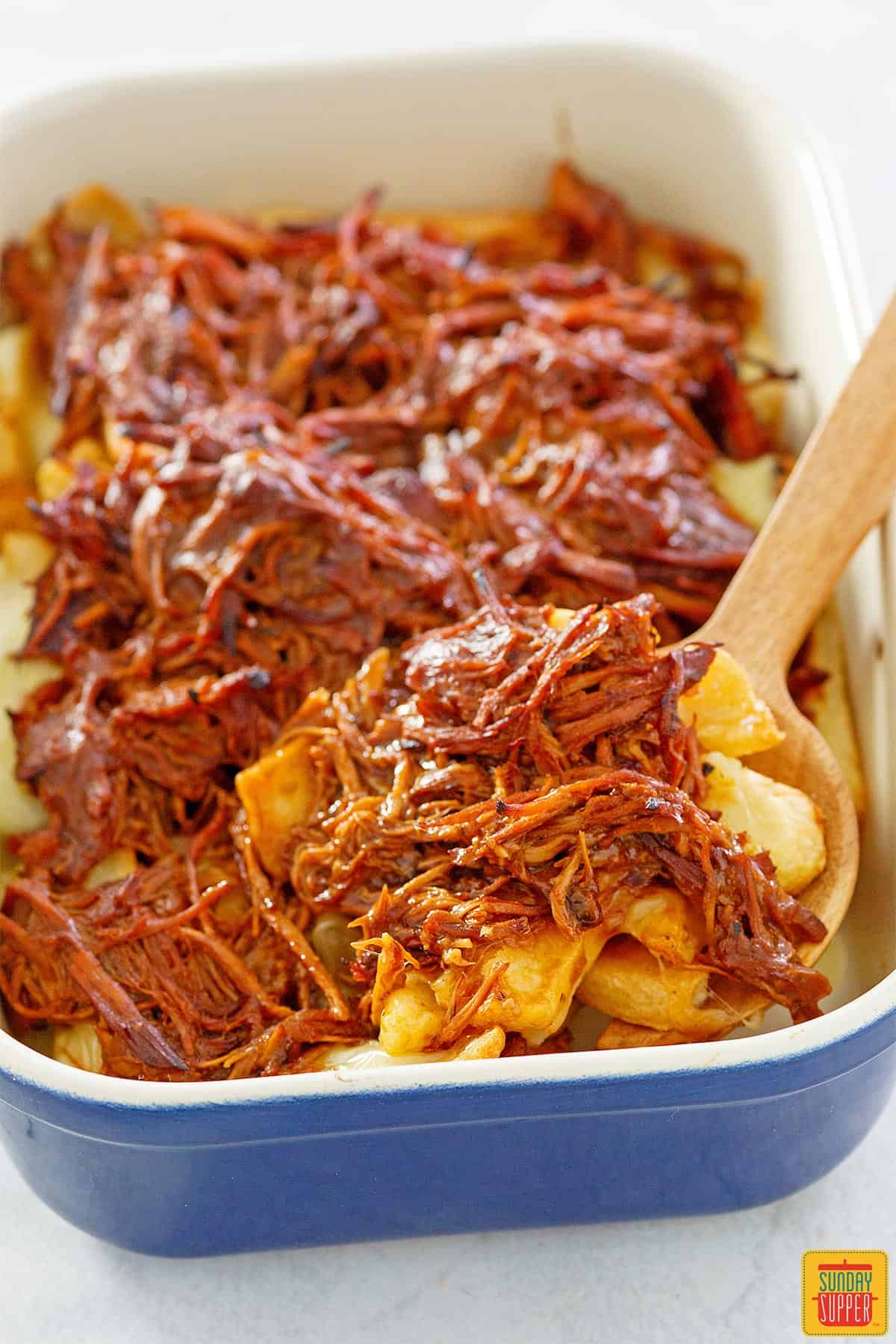 Pulled pork poutine in a blue baking dish