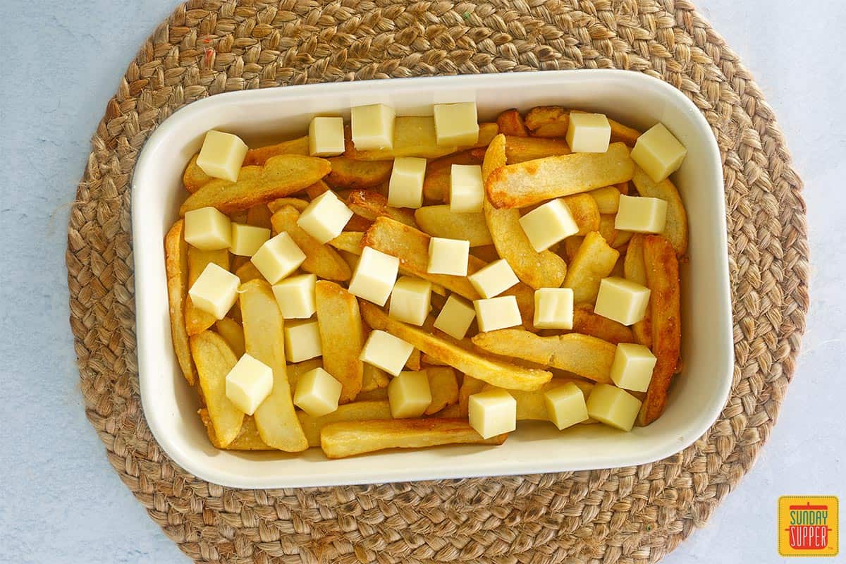 fries in a baking dish topped with cheese curds
