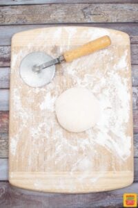 pizza dough rolled in a ball on a floured cutting board