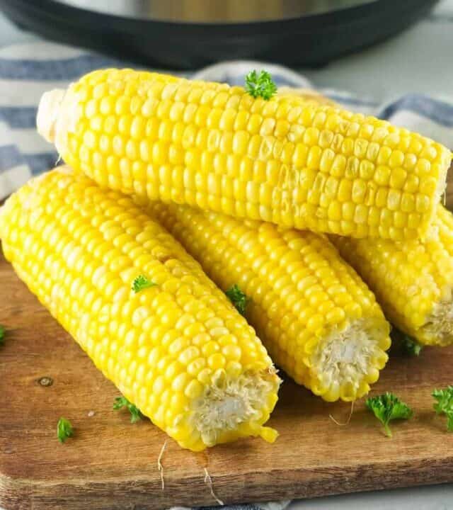 corn on the cob on a cutting board in front of an instant pot