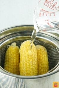 Pouring water into instant pot with corn