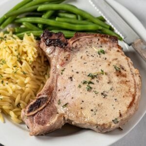pan seared pork chops on a plate with green beans and orzo