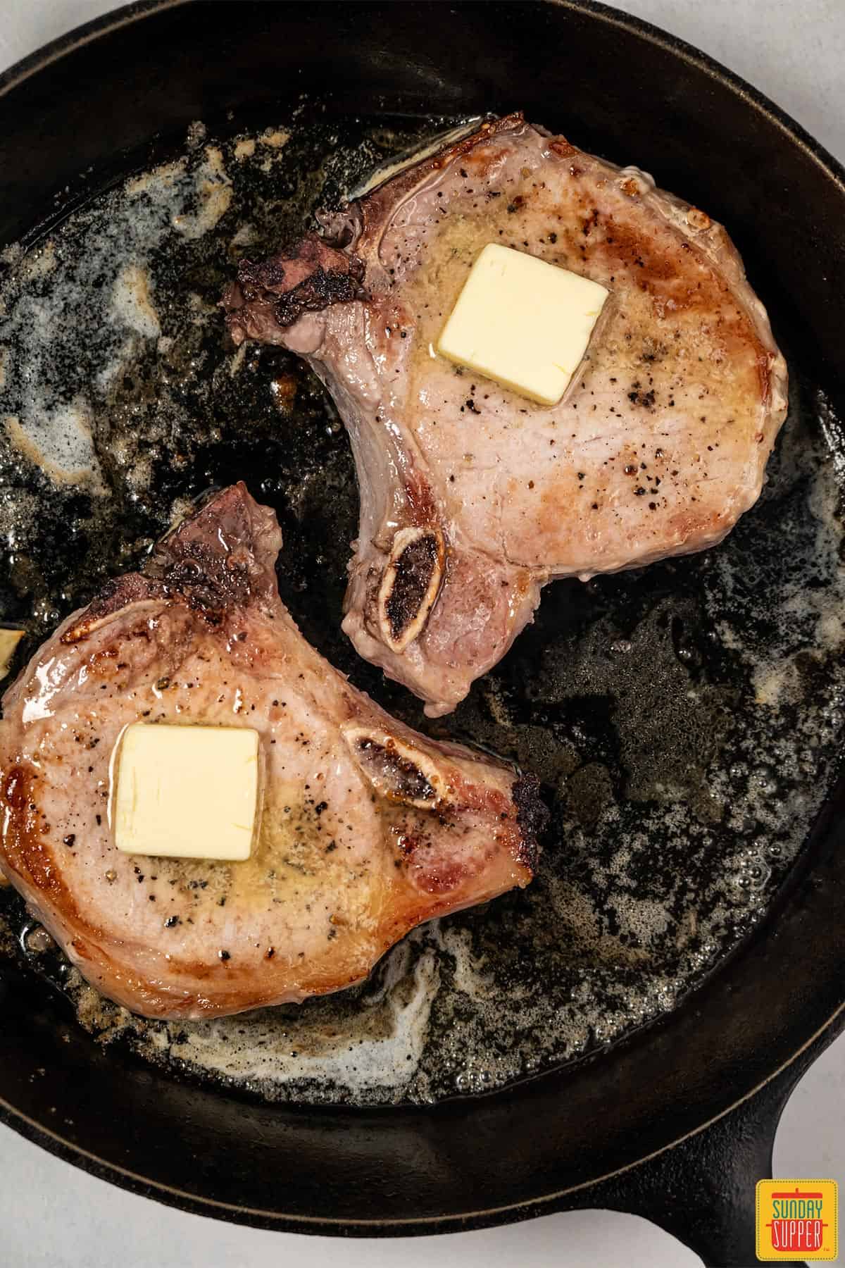 pork chops in a pan with butter
