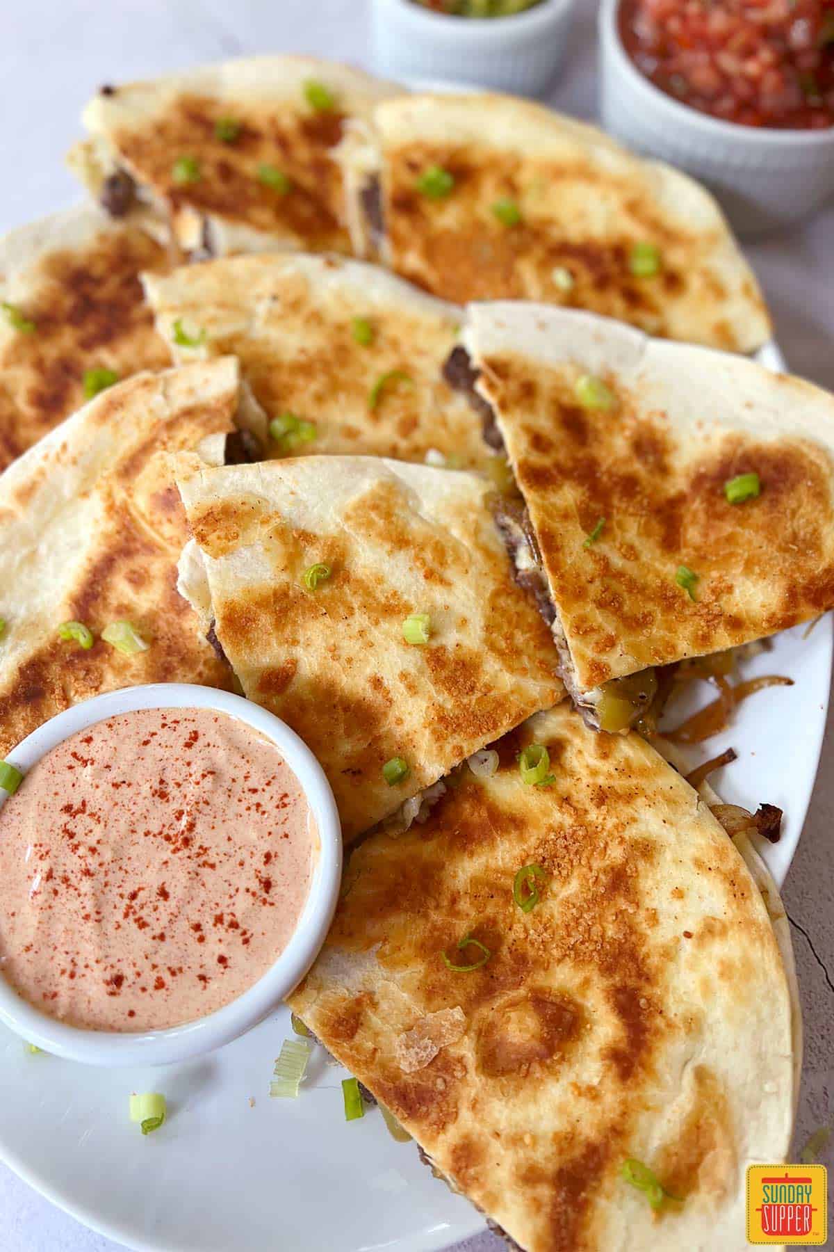 steak quesadillas sliced on a plate with quesadilla sauce