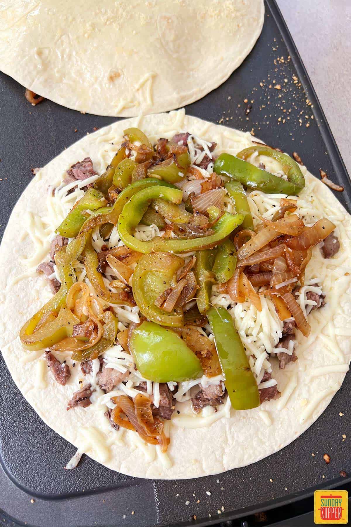 piling quesadilla filling into tortillas to make steak quesadillas