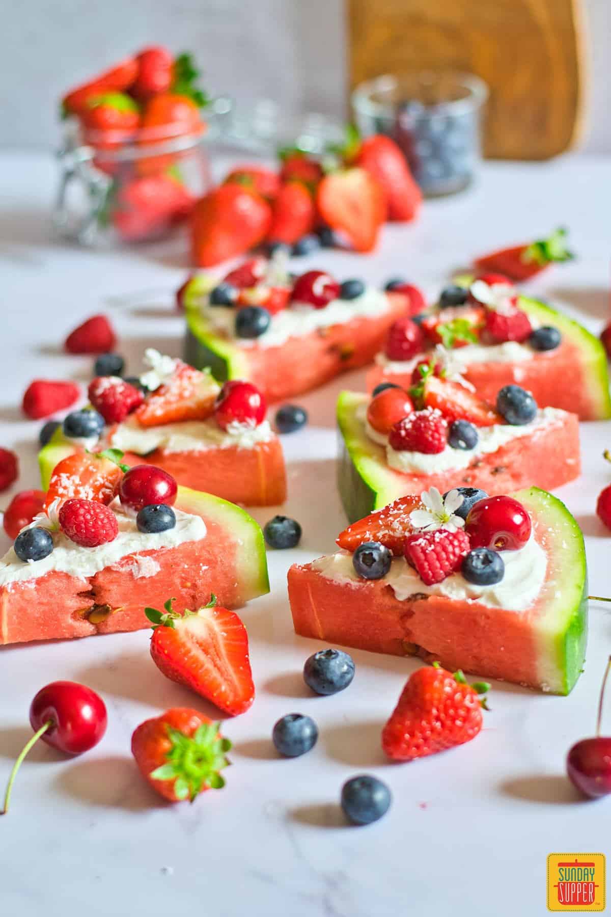 sliced watermelon pizza surrounded by fresh fruit