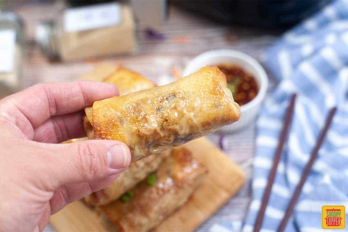 holding an air fryer egg roll between two fingers