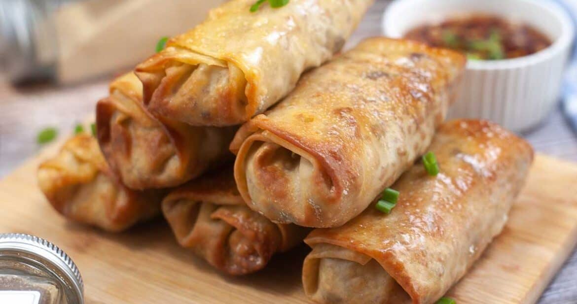 stack of air fryer egg rolls on a wooden serving board