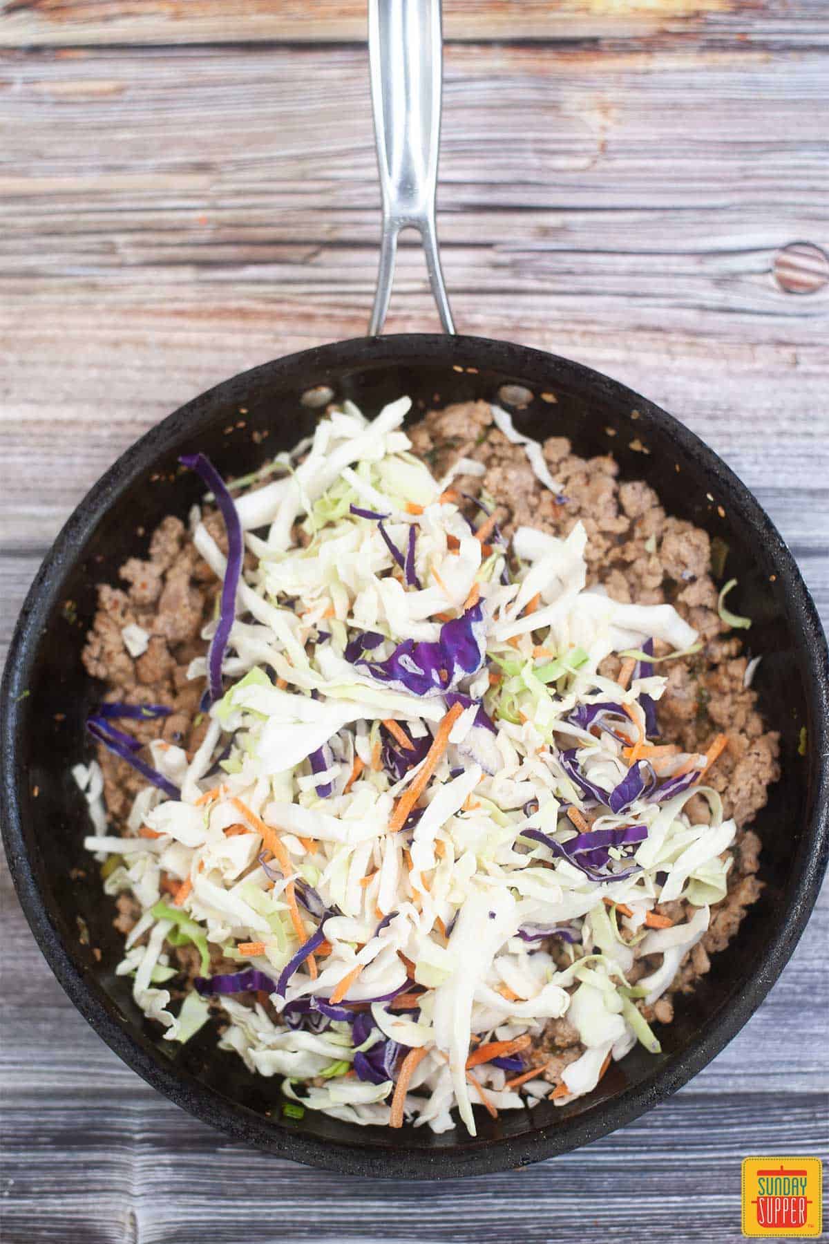 adding slaw mix to pork in a pan