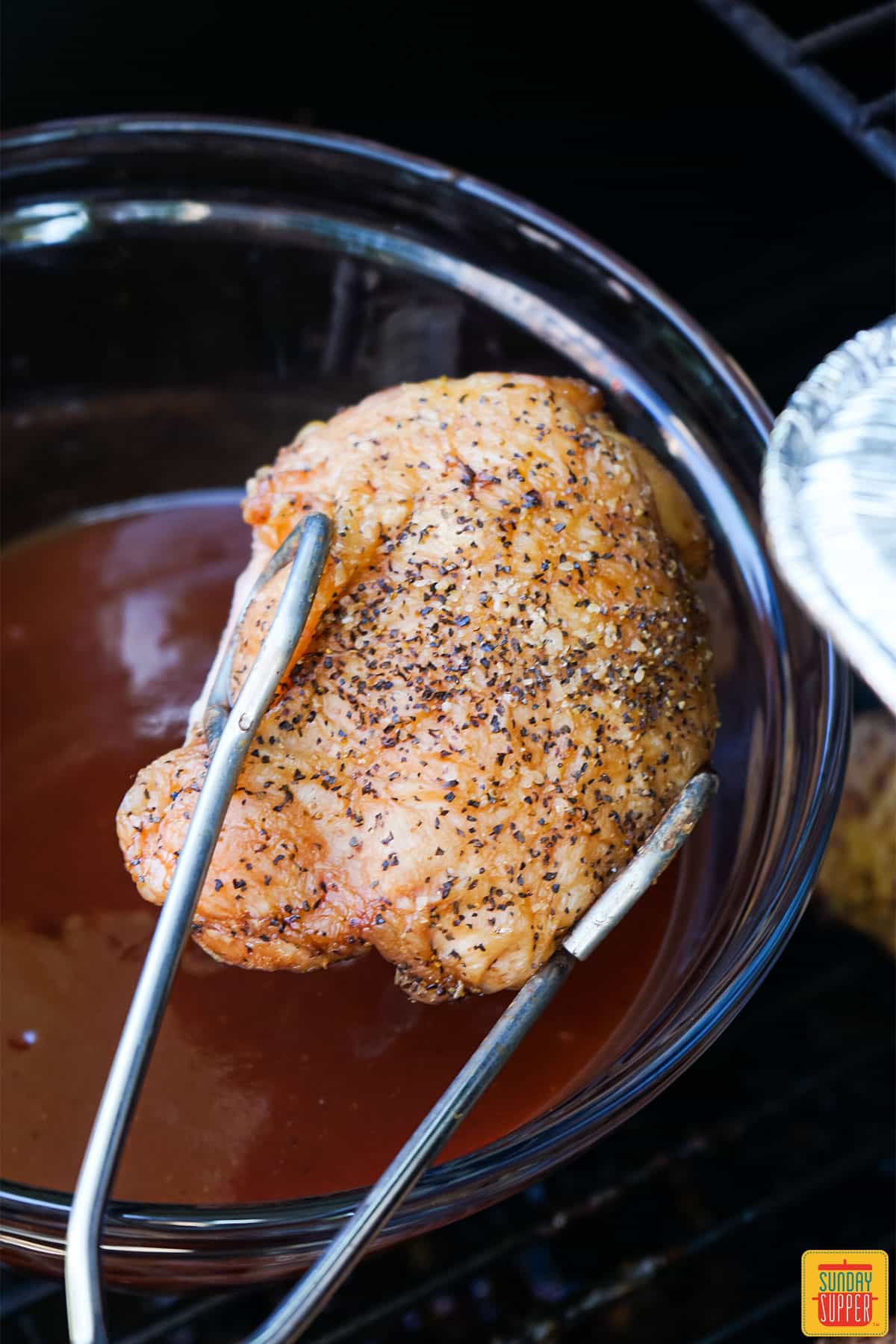 Dipping a chicken thigh in BBQ sauce
