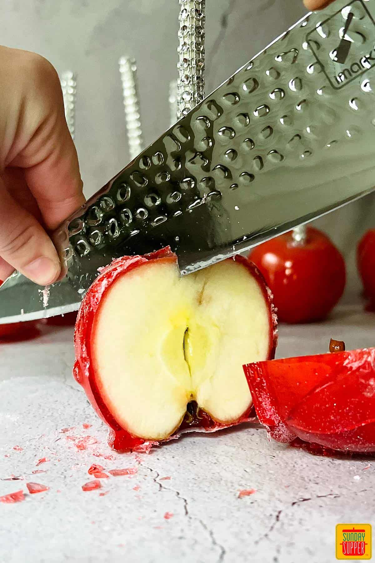 red candied apples being cut in half with a knife