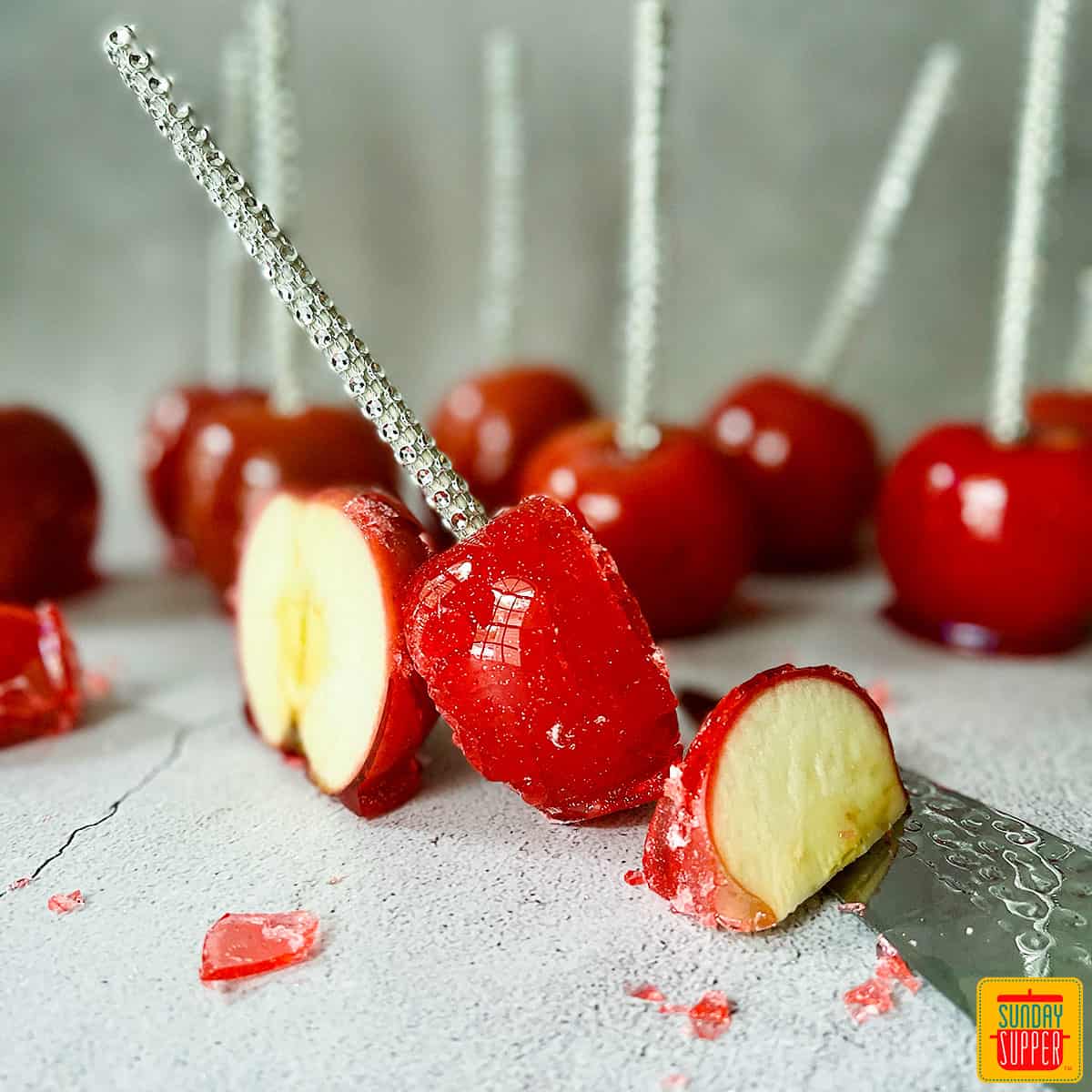 red candied apple slices with a knife