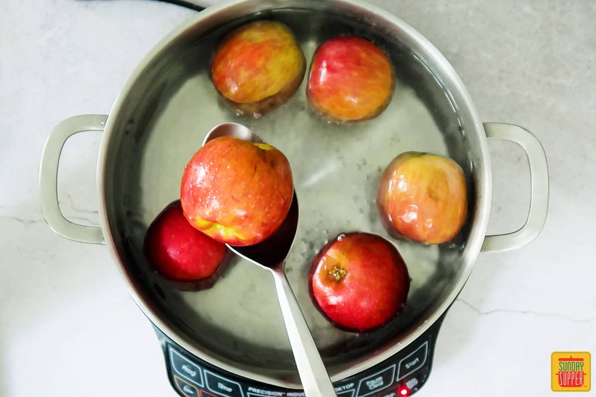 removing apples from boiling water for candied apples recipe