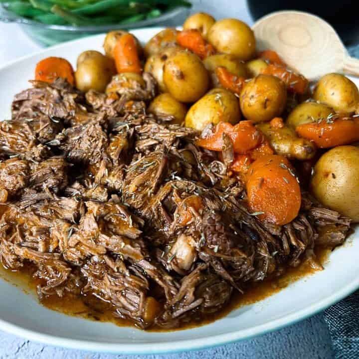 close up of instant pot chuck roast on a plate with carrots and potatoes