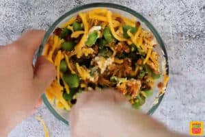 mixing jalapeno popper pinwheel sandwich ingredients in a bowl