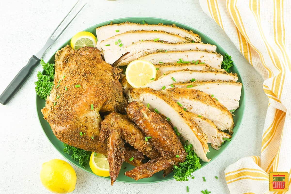 spatchcock turkey sliced on a plate with lemon slices