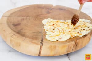 honey overtop smeared butter on a wood cutting board