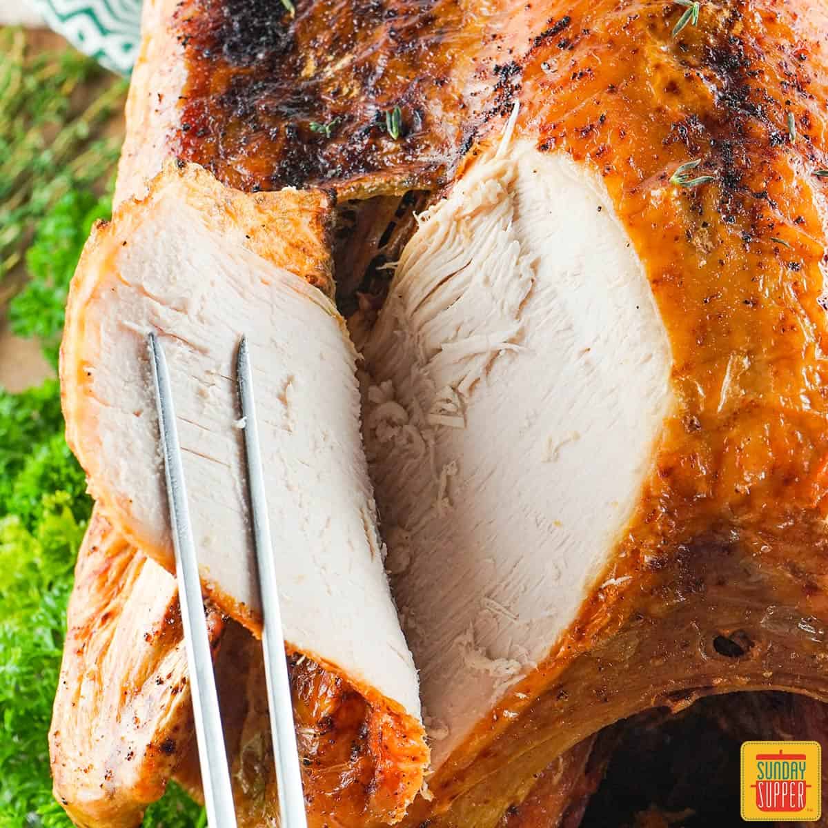 cutting a slice of deep fried turkey over a bed of parsley