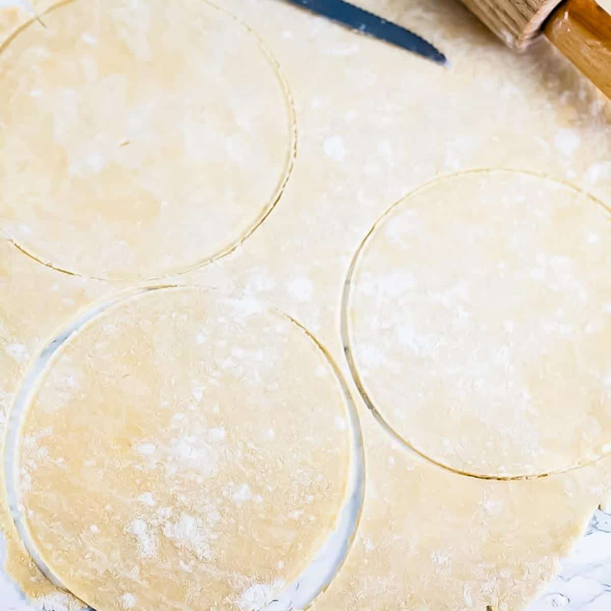 cutting circles of empanada dough from a sheet of dough