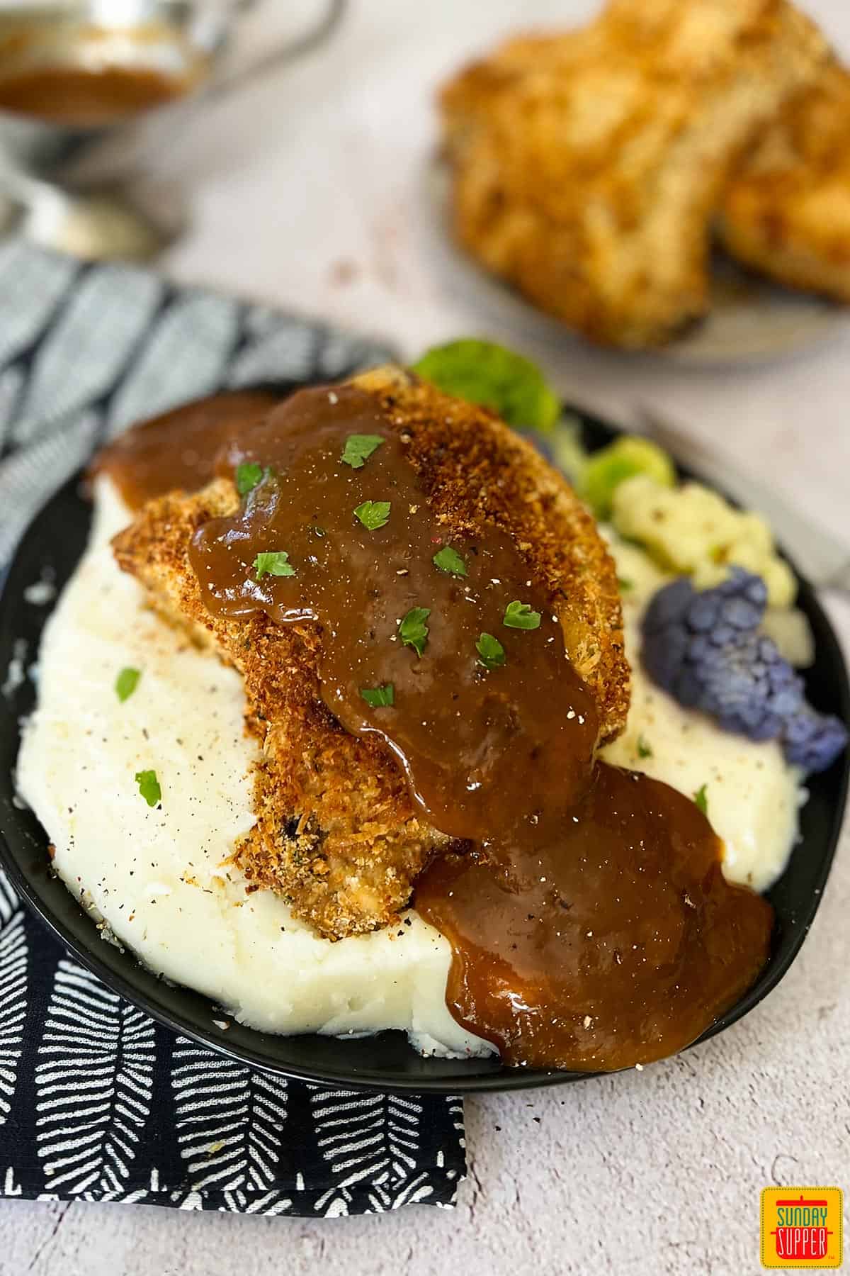 oven baked pork chops over mashed potatoes with pork gravy